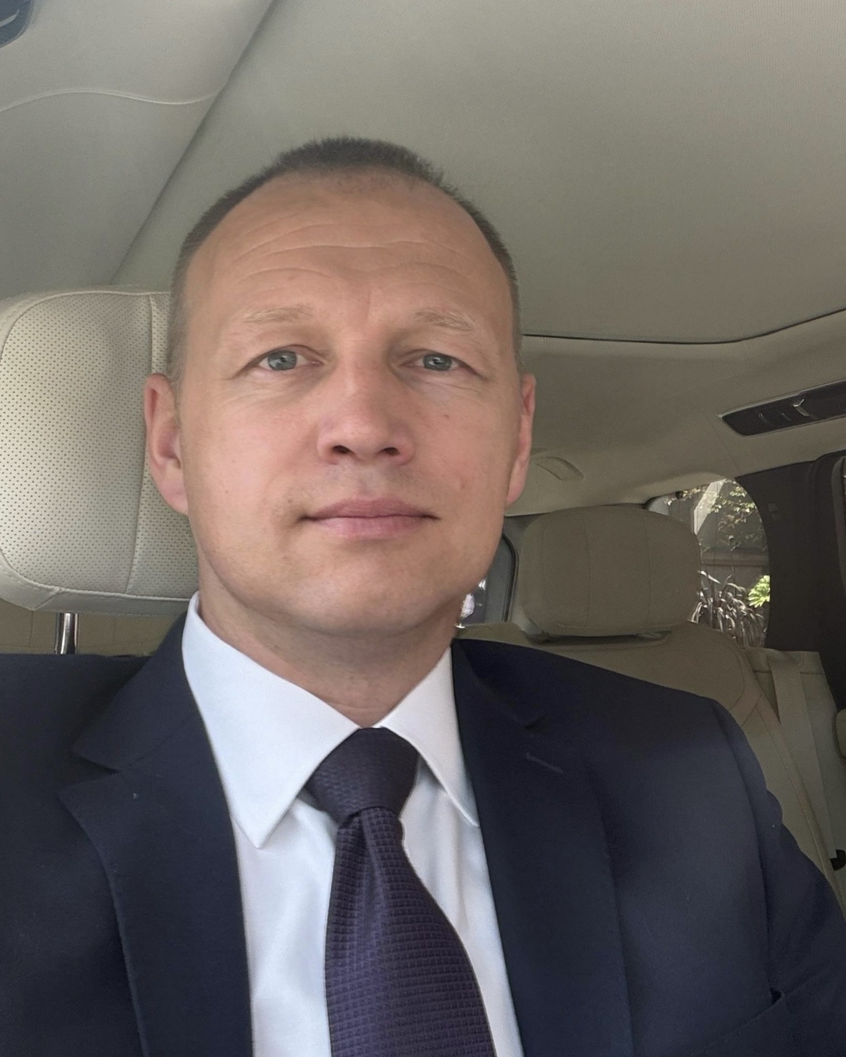 Portrait of the owner-operated Range Rover chauffeur in London, wearing a suit and tie inside the Range Rover Autobiography